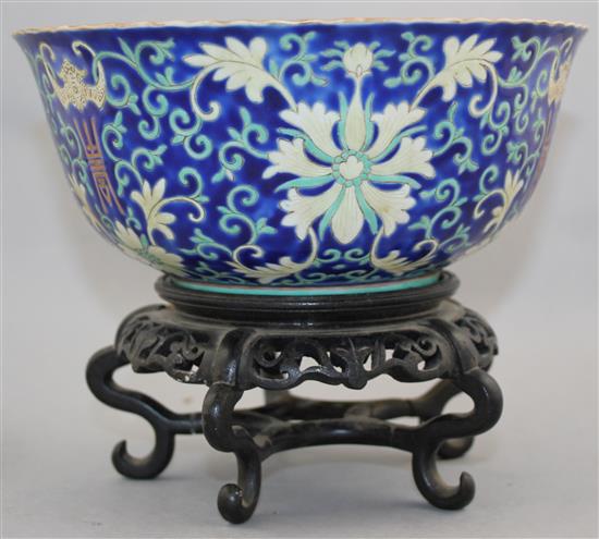 A Chinese blue ground porcelain bowl, Qianlong mark, late 19th / early 20th century, 21.5cm diam., wood stand